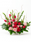 Floral arrangement with red and pink roses and greenery on a white background