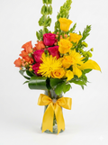 Bouquet of flowers with orange, yellow and pink roses in a clear vase on a white background