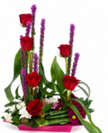 Floral arrangement with red roses, purple flowers, and green leaves on a white background