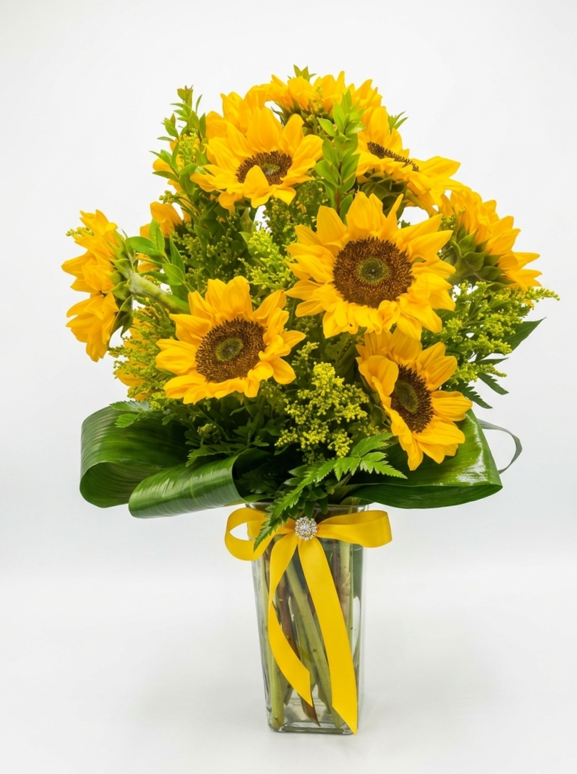Bouquet of sunflowers in a clear vase with a yellow ribbon on a white background
